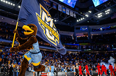 Photo of mascot carrying a Marquette flag across basketball court. Link to Life Stage Gift Planner Under Age 60 Situations.